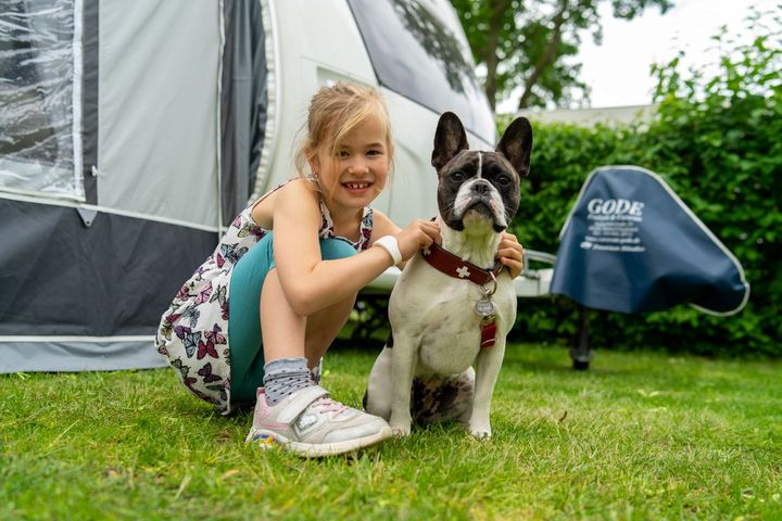 Mädchen mit Hund vor einem Wohnwagen